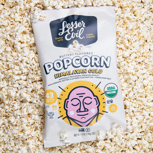 Popcorn bag with Lesser Evil branding on a bed of popcorn.
